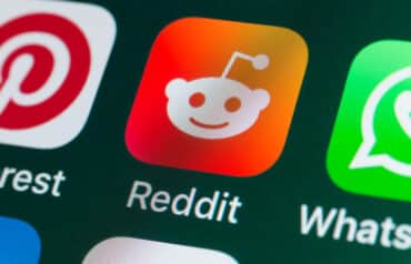 Close-up of the Reddit logo (a white alien mascot on an orange background) displayed on a smartphone screen, illustrating the topic of Law Firm Reddit Marketing and social media strategy.