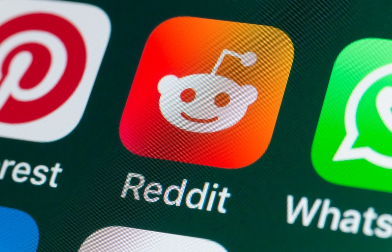 Close-up of the Reddit logo (a white alien mascot on an orange background) displayed on a smartphone screen, illustrating the topic of Law Firm Reddit Marketing and social media strategy.