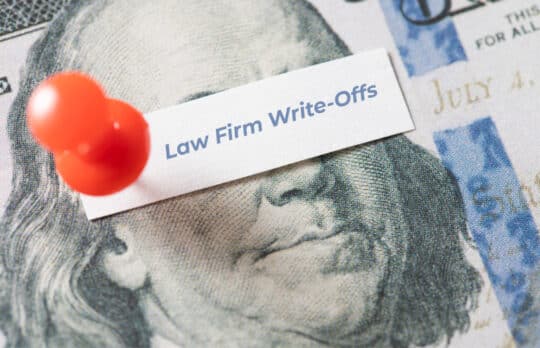 Close-up of a $100 bill with a red pin holding a note that reads Law Firm Write-Offs.