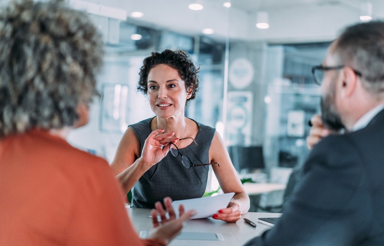 Three professionals collaborating around a table in a modern office, demonstrating strong attorney client communication.