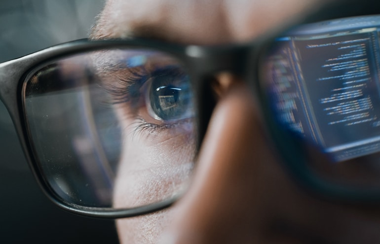Close up of eyeglasses reflecting digital data and document code strings, representing a lawyer tech tips workflow.