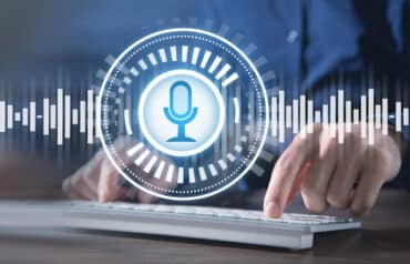 A hand typing on a keyboard with a digital graphic of a microphone and audio waves representing dictation tools for lawyers.