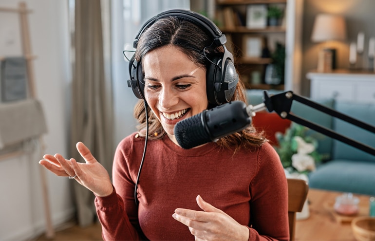 A smiling lawyer with headphones speaking into a microphone while recording a show on podcasting for lawyers