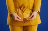 Professional woman in a yellow suit holding autumn leaves, highlighting the importance of menopause policies in law firms.