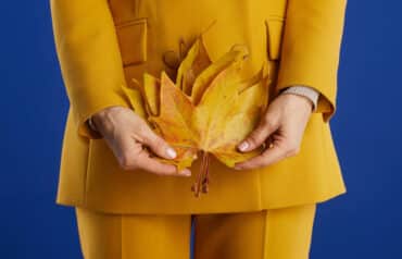 Professional woman in a yellow suit holding autumn leaves, highlighting the importance of menopause policies in law firms.